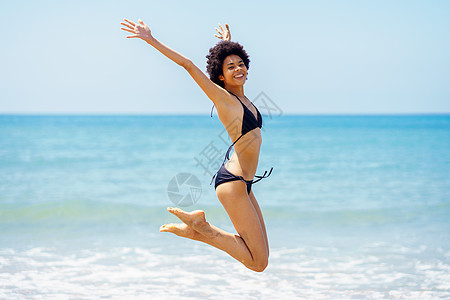 快乐的黑女人夏天在海边跳跃图片