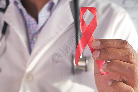 持有带有复制空间的红色艾滋病毒丝带的医生手图片