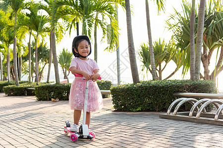 快乐的亚洲小女孩穿着安全头盔 在夏日在露天公园户外的路上玩粉红色踢踏板公园骑术活动乐趣女性闲暇运动孩子们微笑女孩图片