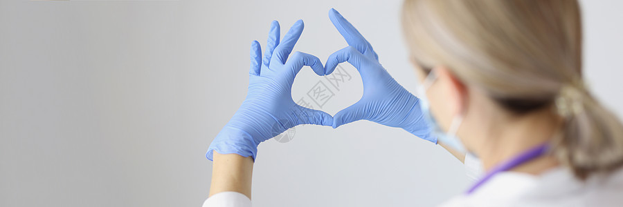 医务工作者用手戴防护手套形成心脏 并佩戴保护手套图片