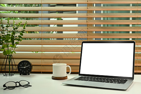 白桌上带空屏幕 咖啡杯 眼镜和家用植物的电脑笔记本电脑图片
