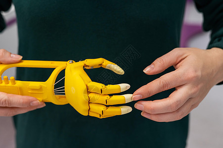 一名妇女展示了印在3D打印机上的塑料儿童假肢手电子人截肢自动化孩子们工厂女性药品进步手臂骨科图片