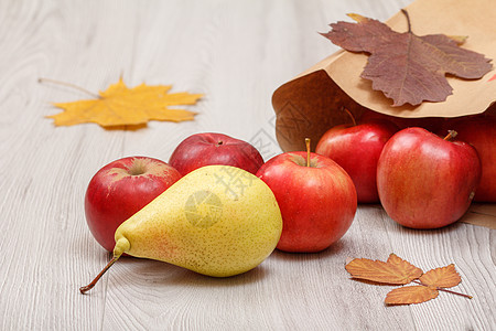 在木制桌子上装有纸袋的梨子和红苹果图片