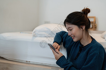 使用智能手机打字 在卧室聊天盒里聊天 社交媒体制造概念等手艺快乐的亚洲女性手工作技术电话电脑视频女士沙发商业成人长椅图片