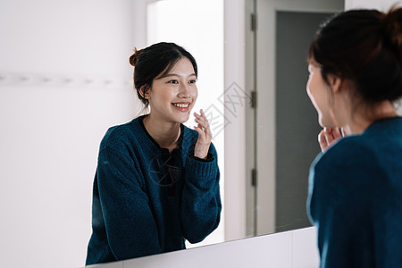 美丽的亚洲女人的肖像 在镜子里看着她的脸图片