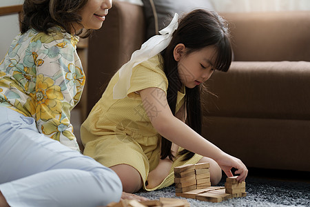 女孩在家里和祖母一起玩木制Jenga建筑师 在家为孩子开展休闲活动爸爸父亲祖父母姐姐朋友妈妈喜悦快乐构造竞赛图片
