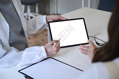 女医生在数字平板电脑屏幕上指向她的女病人 并向她解释诊断结果图片
