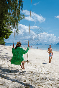 泰国普吉岛附近热带岛屿纳卡岛海滩上的一对男女 海滩秋千上的女人和散步的男人自由假期夫妻晴天幸福天堂太阳女士中岛女性图片