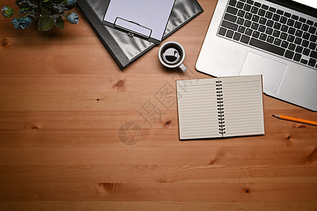 使用笔记本电脑 笔记本和木制桌上剪贴板的简单工作空间图片