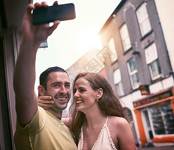 自拍是最好的旅行纪念品 拍摄一对快乐的年轻夫妇在探索外国城市时自拍图片
