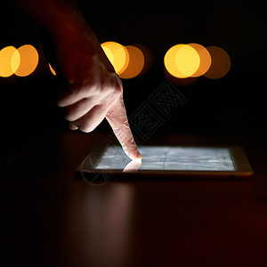 工作时间过晚 用数字平板电脑在黑暗中近距离拍摄一根手指头的镜头背景图片