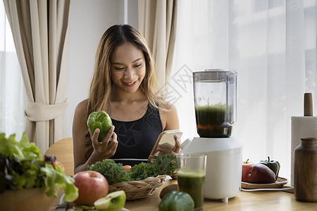 健康的年轻女子在厨房里用新鲜蔬菜和水果做绿色解毒冰淇淋图片