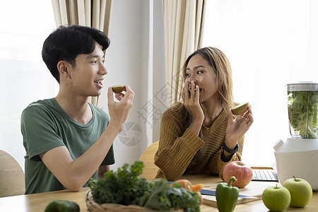 快乐的一对年轻夫妇一起在厨房做素食晚餐图片