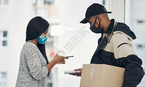 限制现金 免费联系 一对蒙面的年轻男女在送货上门时使用智能手机的镜头图片