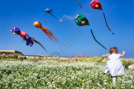 一个小女孩跑过田野 带着风筝飞向清蓝的天空图片