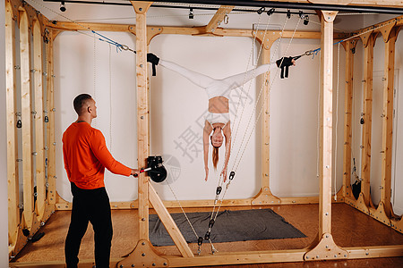 教练在人体拉伸模拟器上拉着身穿运动服的女孩的绳索力量紧张自重火车活力精神女性肌肉结构身体图片