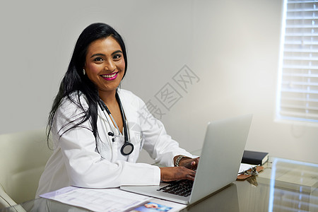紧跟最新的医学突破 一位女医生在她办公室的笔记本电脑上工作的画像图片