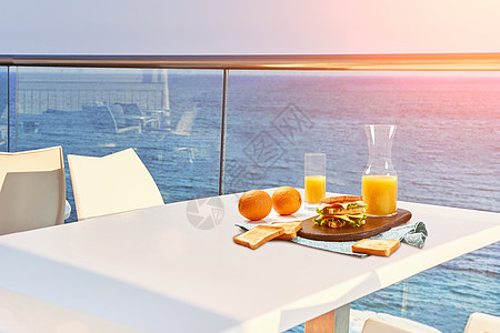 两人在露天旅馆阳台有海景的桌边吃早餐托盘太阳耀斑干杯咖啡店假期旅游蓝色桌子旅行自拍图片