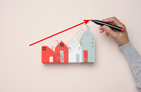 一个小型木屋和一个女人的手 绘制了一张图表 上面有不断增长的指标贷款商业进步销售房子价格金融住宅建筑红色图片