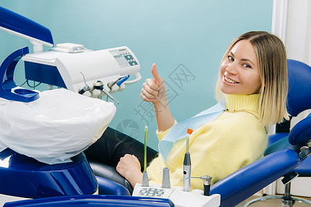 美丽的女病人坐在牙医的椅子上 用她的手在课堂上表演时成人手指微笑保健女士卫生医院牙科医生喜悦图片