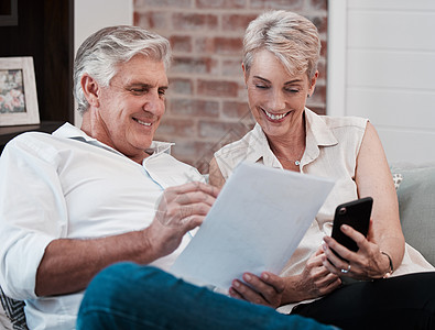 健康应该是你最大的目标 一对成熟的夫妇在看文书工作时使用手机在家沙发上拍到的镜头图片