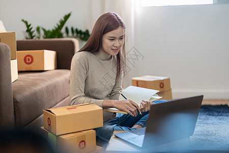 亚裔女性在家做生意 在线购物 年轻的小企业主在工作场所包装纸箱 在线销售或电子商务自由职业者纸板中小企业产品商务互联网客户企业家图片