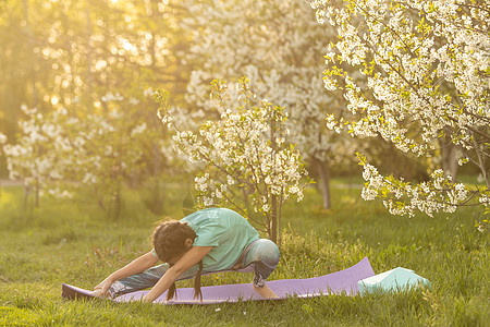 一个小女孩做瑜伽 躺在公园体育垫子上 健康的生活方式是一种幼稚习惯 笑声生活后院快乐童年青年喜悦花园训练活动孩子图片