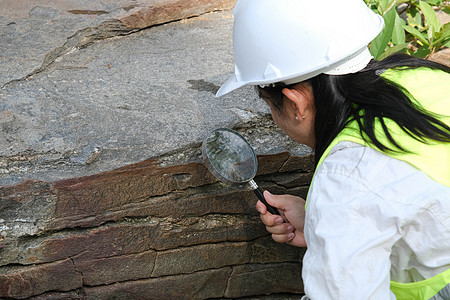 亚洲女地质学家研究员在自然公园用放大镜分析岩石 现场勘探地质学家 石头和生态概念考古学探索森林地质学检查历史学习河岸旅行全球图片