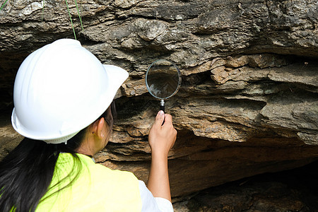 亚洲女地质学家研究员在自然公园用放大镜分析岩石 现场勘探地质学家 石头和生态概念地质学教育森林历史环境侵蚀科学河岸旅行学习图片