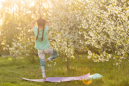 一个小女孩做瑜伽 躺在公园体育垫子上 健康的生活方式是一种幼稚习惯 笑声后院青年生活运动训练后代冥想活动喜悦女孩图片