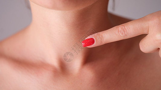 红修指甲的妇女将手指对着颈部区域 与甲状腺密闭图片