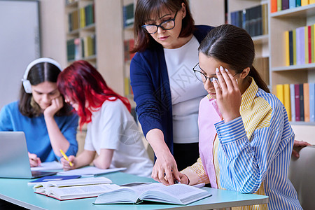 青少年学生群体和在图书馆书桌上的师范学习团体知识多样性课堂桌子电脑课程笔记本教科书班级图片