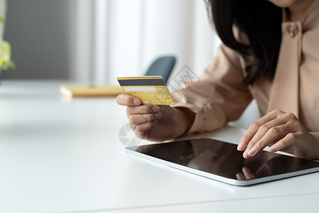 特写持有银行信用卡的女性 并在数字平板电脑上键入用于在线购物 购买商品或在线订购 输入银行账户和在线银行报价中的详细信息图片