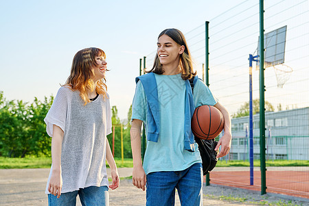 在篮球法庭附近露户行球的年轻少男女青年男女学生女孩成人友谊大学法庭快乐女性男性中学街道背景图片