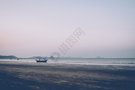 在夕阳下的沙滩上行走的人的剪影 俯瞰大海的海滩和山脉 海中的小船图片