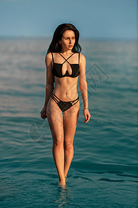 穿着黑色泳衣的海边年轻美女 享受着她的度假节日身体石头假期长发海洋寒意泳装女性比基尼游泳衣图片