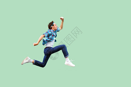轻绿色背景的随意风流感性男人的肖像格子运动飞跃自由活力舞蹈潮人蹦床成功衬衫图片