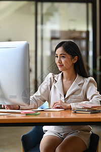 充满自信的亚洲女商务人士与现代计算机合作 (笑声)图片