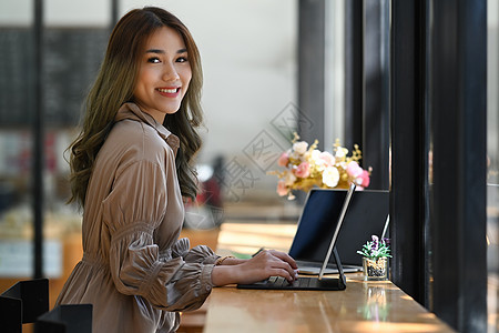 迷人的女商务人士坐在现代咖啡店里 对着镜头微笑图片