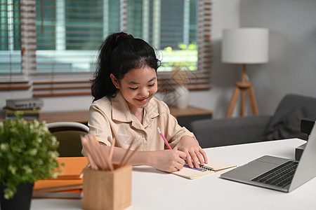 在家用笔记本电脑在网上学习的亚洲快乐儿童做功课图片