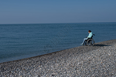 在海边坐轮椅的 土化的caucasians女人晴天自由闲暇保健卫生事故保险喜悦车轮蓝色图片