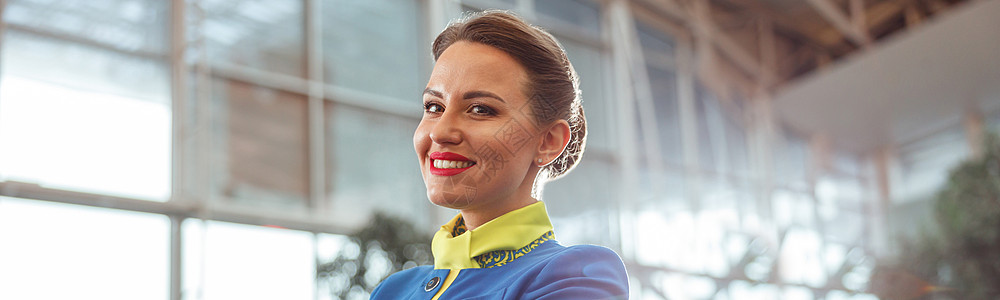 在机场候机站站着的愉快的女航空工人旅行手套国际航空公司宪章工作航班微笑服务员运输图片