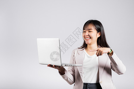 使用笔记本电脑和用手指对着屏幕握住脸并举起手来微笑图片