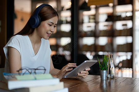 微笑的亚洲青少年戴着耳机看着平板电脑听和学习在线课程 快乐的中国女商务人士戴着耳机视频通话 在线教育理念图片
