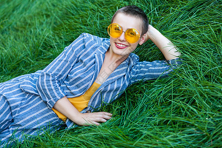 美丽的女孩在夏日享受青草的青草潮人条纹眼镜快乐公园成功化妆品幸福露齿衬衫图片