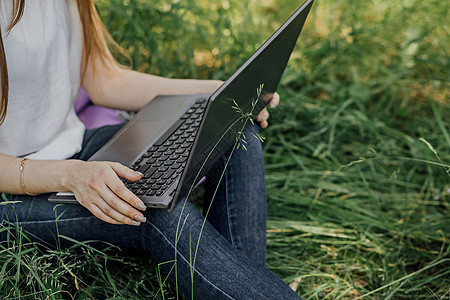 女孩坐在草地上 在笔记本电脑上工作 自由职业者图片