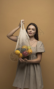 生态友好型生活方式和健康饮食概念 零浪费 穿米衣的黑发女人拿着可再使用的网目购物袋 带新鲜水果和蔬菜图片
