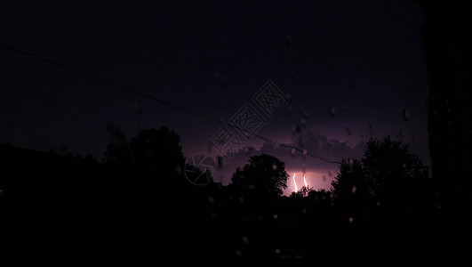 夜间闪电在树边的村子里下雨图片