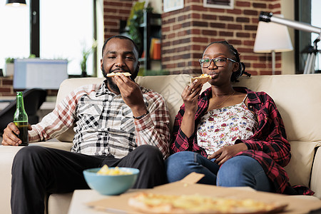 非裔美国人夫妇吃一块比萨饼 喝几瓶啤酒图片