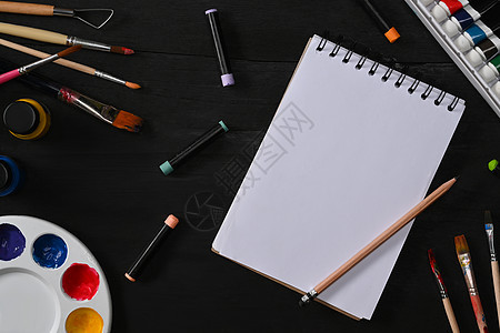 黑木桌上的速写本 画笔 管漆 水彩和调色板 艺术家工作区 艺术 车间 绘画 创意概念图片